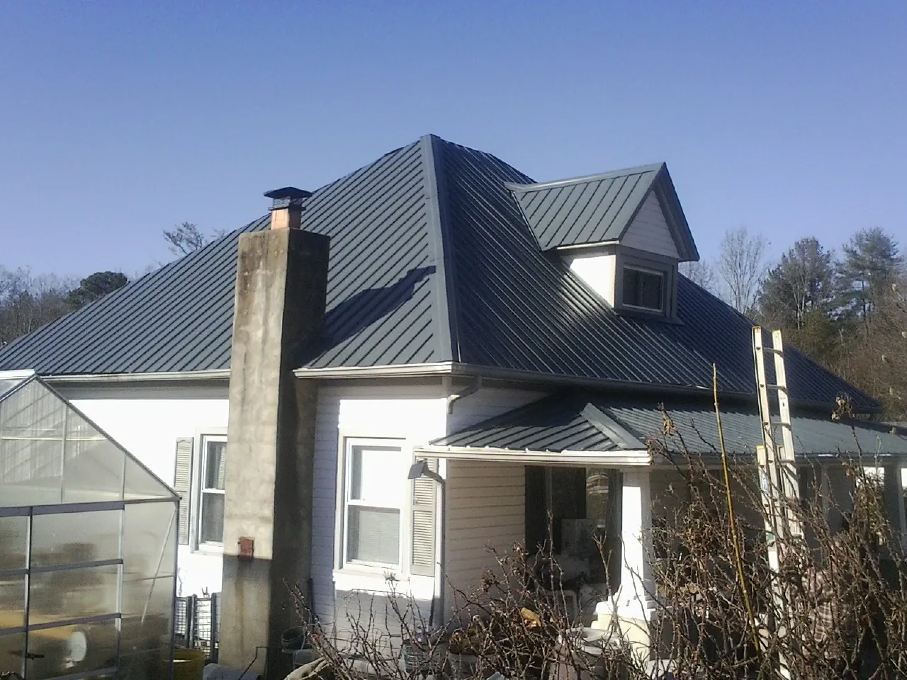Dark blue standing seam metal roof on a white farmhouse with dormer — Slate & Tile Roof Repair by Roofing Brothers in San Mateo
