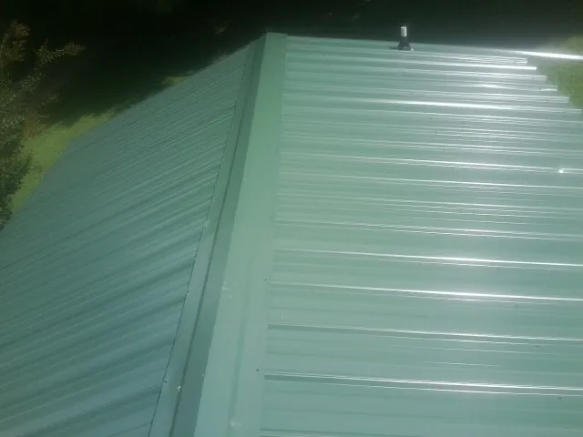 New green metal panels meeting at the ridge of a roof — Flat Roof Repair work by our crew in San Mateo