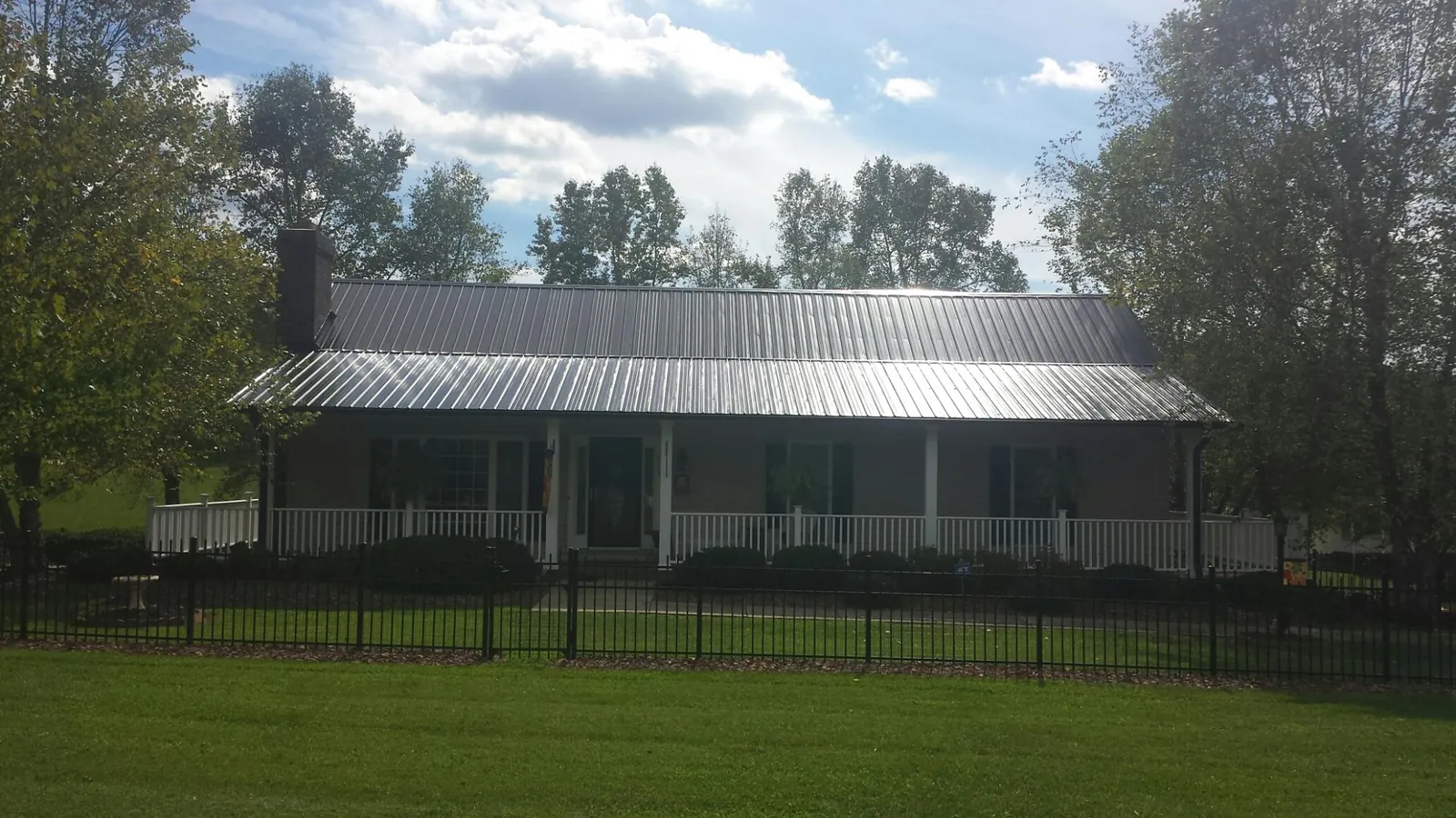 Gray metal roof on a brick ranch with a full width front porch — Gutter Guard Installation work by our crew in San Mateo