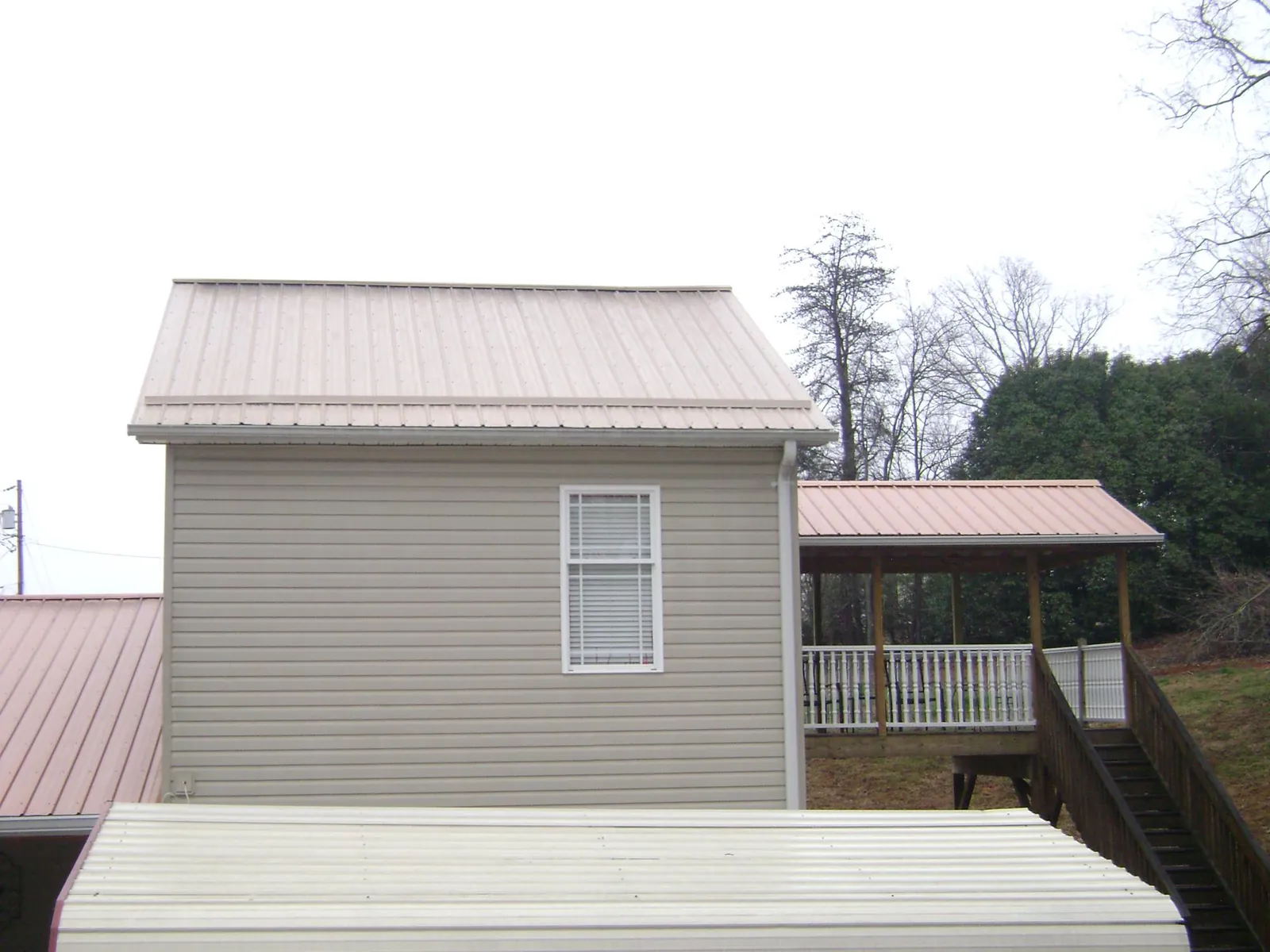 Tan metal roofs on a two story addition and attached porch, from a Roof Replacement job in San Mateo