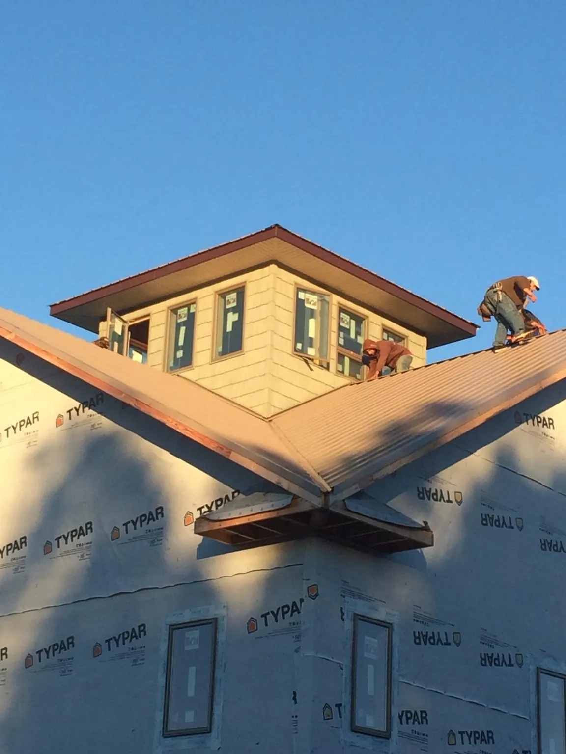 Roofers working around a rooftop cupola on a new metal roof at sunset — Roof Waterproofing in San Mateo by Roofing Brothers